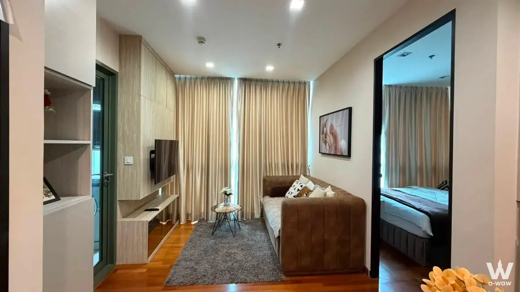 Living room in a WISH Signature Midtown Siam condo showcasing a brown leather sofa, marble coffee table, and built-in media