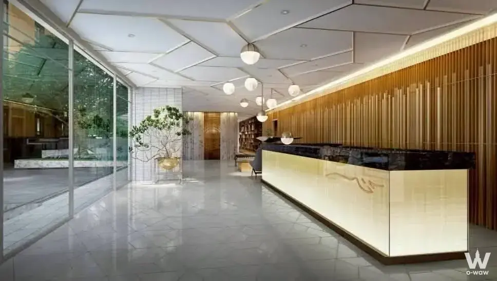 Luxury condo lobby with black granite desk, gold panther logo, and warm pendant lighting at Chalermnit Art De Maison