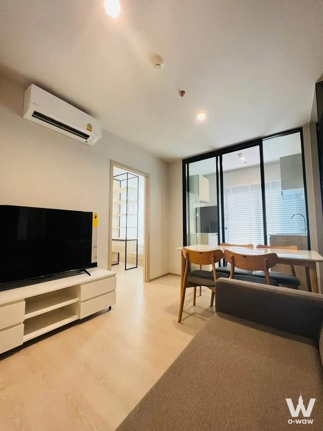Open-plan living space in NUE Noble Ngamwongwan with dining set and glass kitchen doors