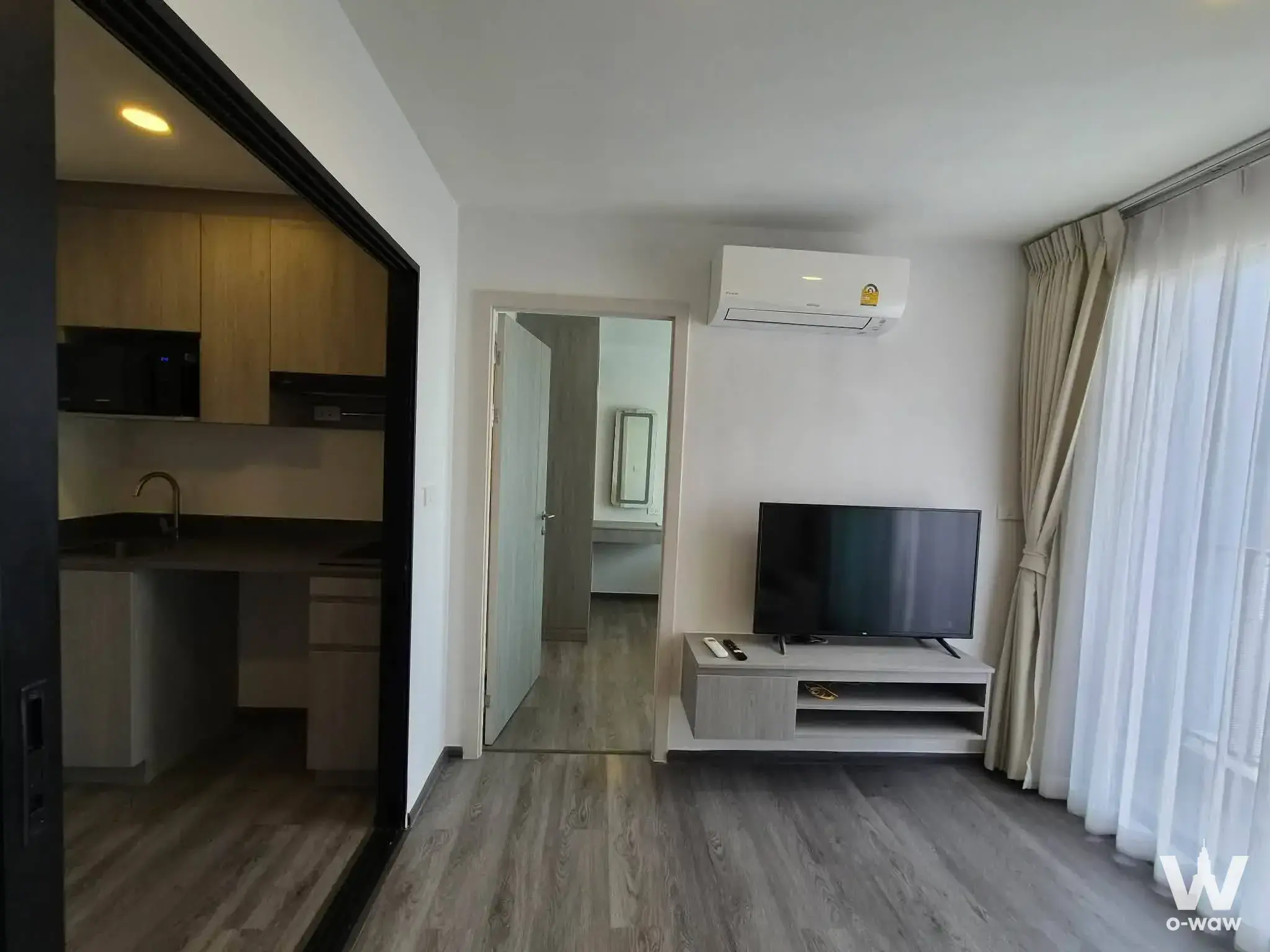 Open-plan living area with oak kitchenette and glass partition in a 1-bed condo for sale at The Origin Onnut