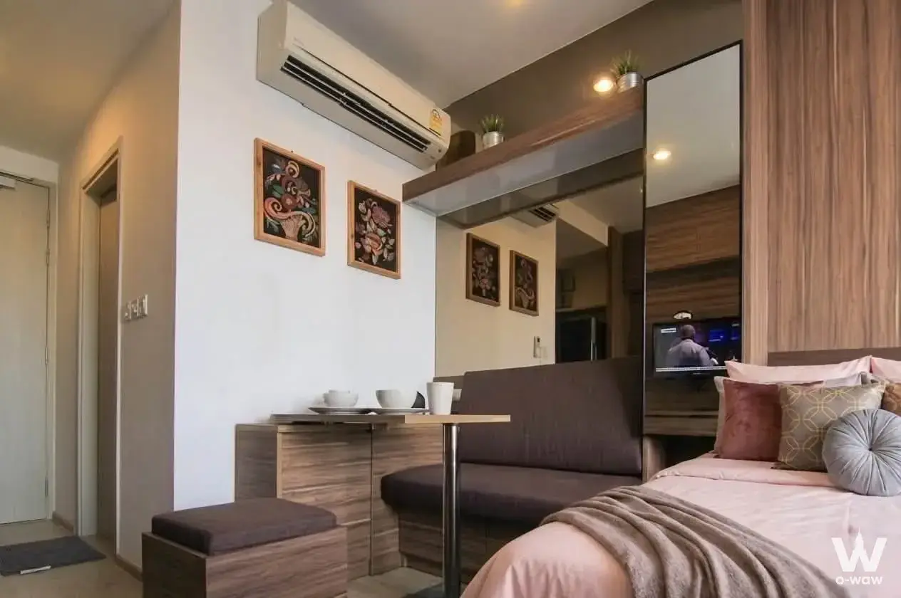 Ideo Q Chula-Samyan 1-bed condo bedroom with pink linens, wood headboard, and built-in bench seating