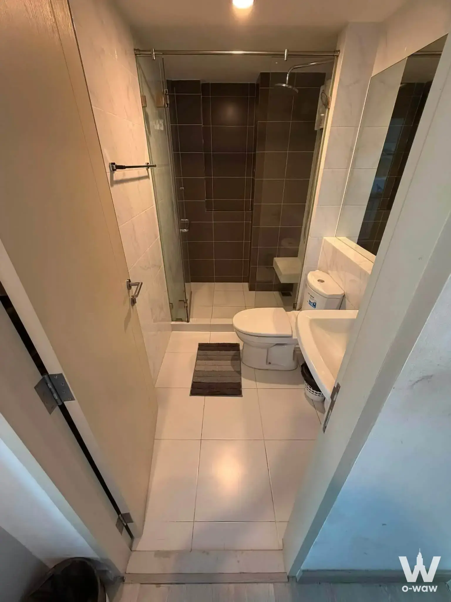 Compact bathroom in a The Niche Mono Sukhumvit 50 listing with white fixtures and dark brown shower tiles