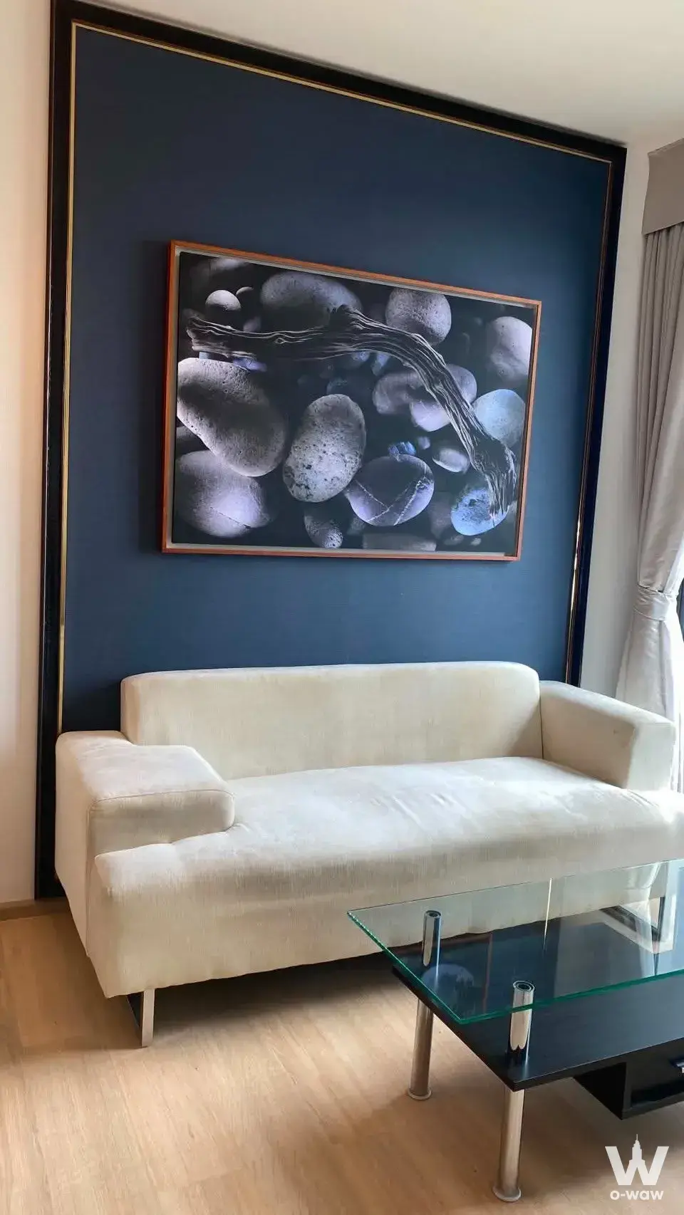 Living area in Rhythm Sukhumvit 42 featuring cream sofa against a navy blue accent wall
