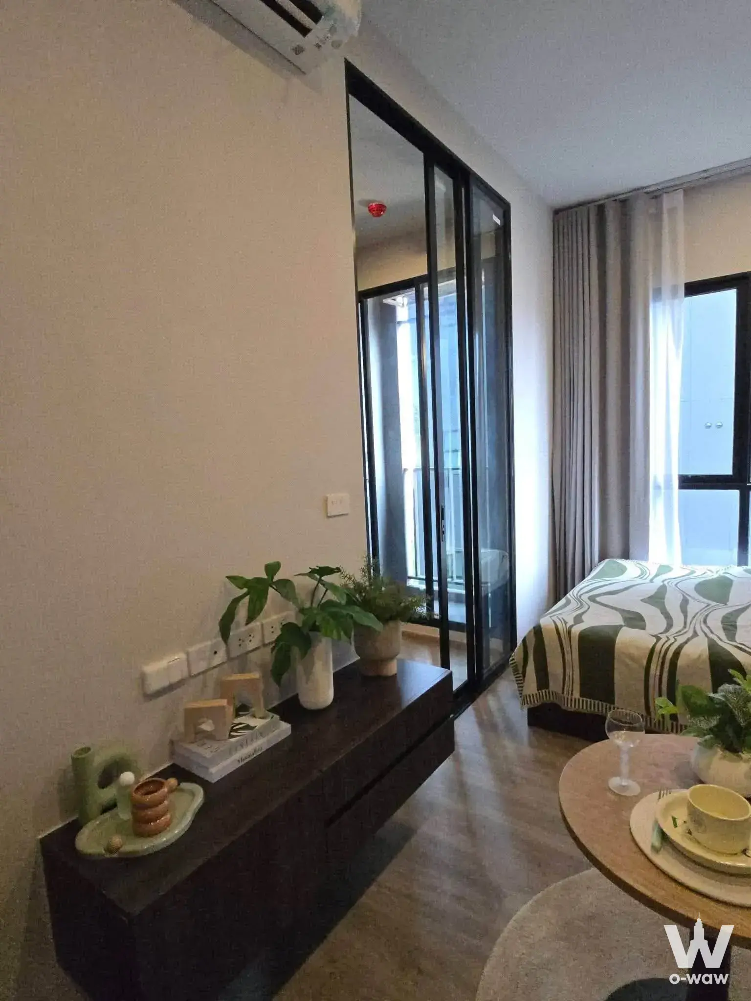 Furnished bedroom in Origin Plug & Play Ramintra featuring floor-to-ceiling glass doors and green duvet
