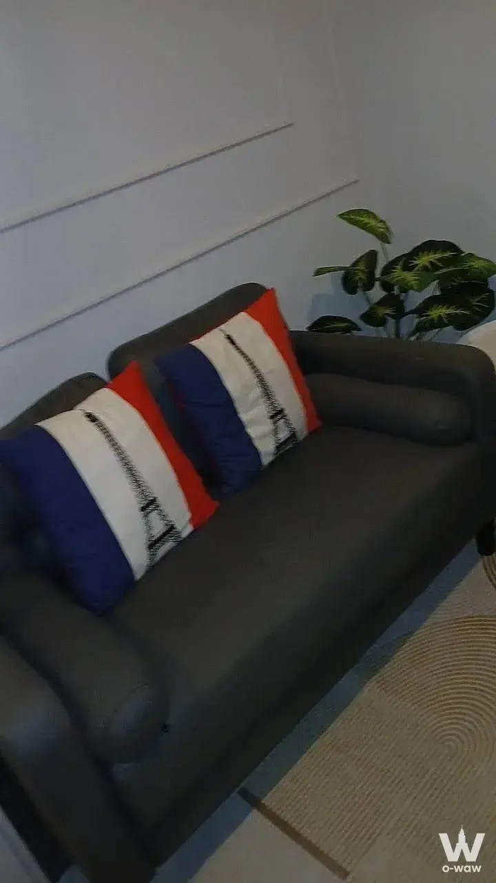 Living corner in Regent Home Bangna with a grey sofa, striped pillows, and a large artificial plant on wood floors