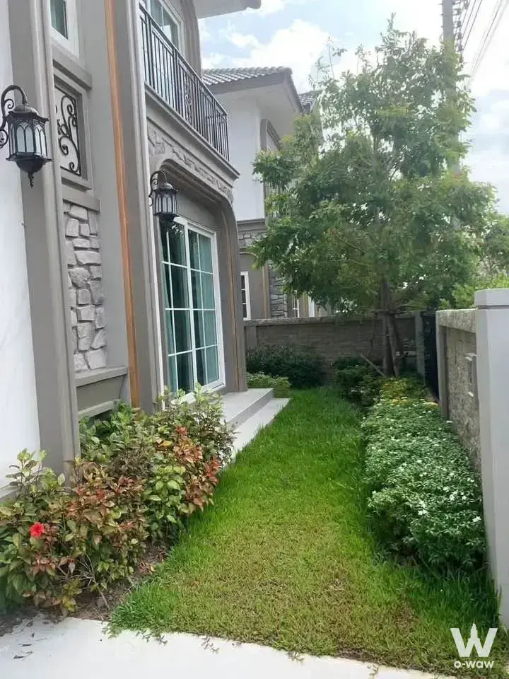 Two-story European-style house exterior with white stucco walls and side garden at Grandio Bangna KM.5