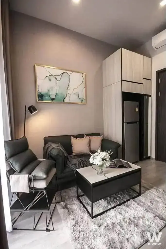 Living area of a THE LINE Sukhumvit 71 condo with a grey sofa, marble coffee table, and floor-to-ceiling cabinets