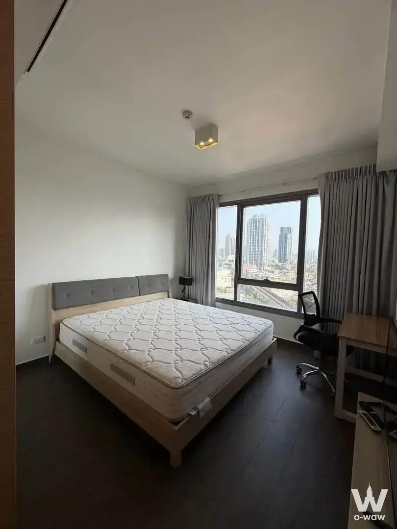 Minimalist bedroom with queen bed and skyline view in this 1-bed unit at The Lofts Ekkamai