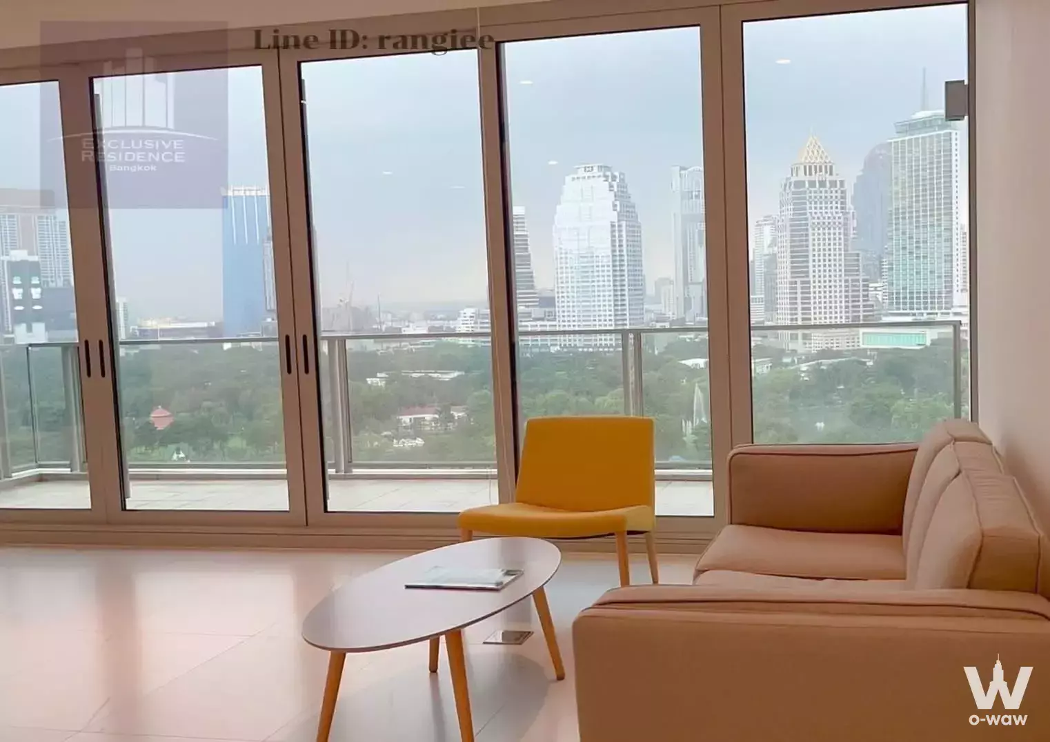 Beige leather sofa and yellow armchair in a 2-bed condo living room at 185 Rajadamri with floor-to-ceiling city views