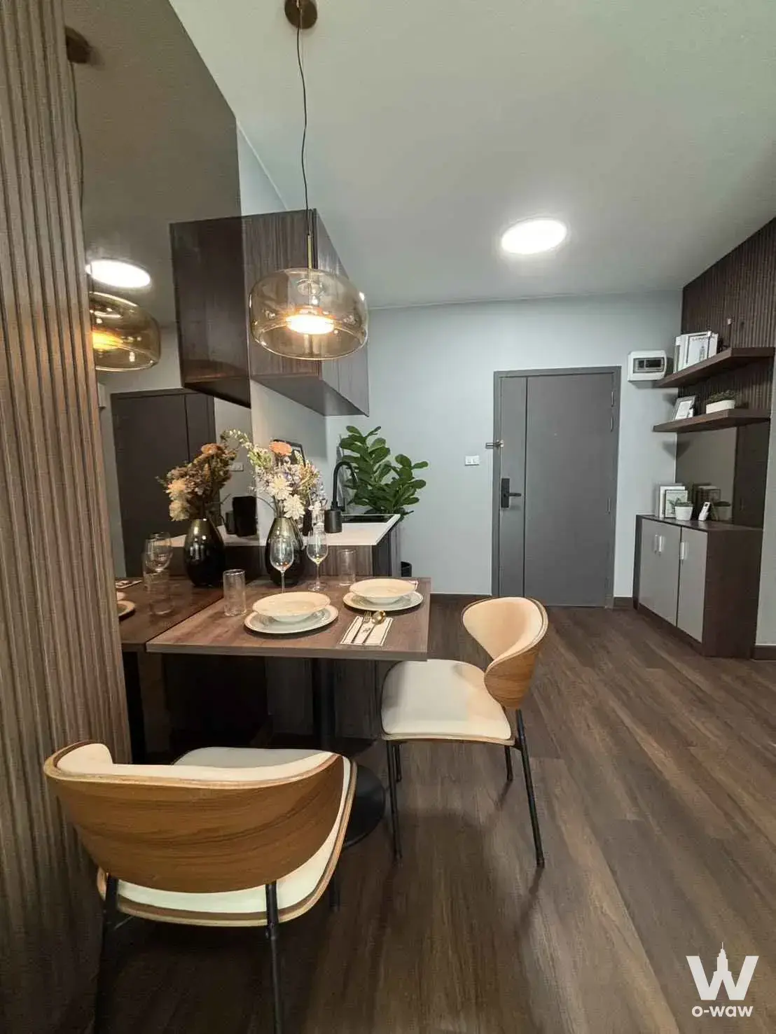 Dining area in a 1-bed Space Condominium for sale with a dark wood table and smoked glass pendant light