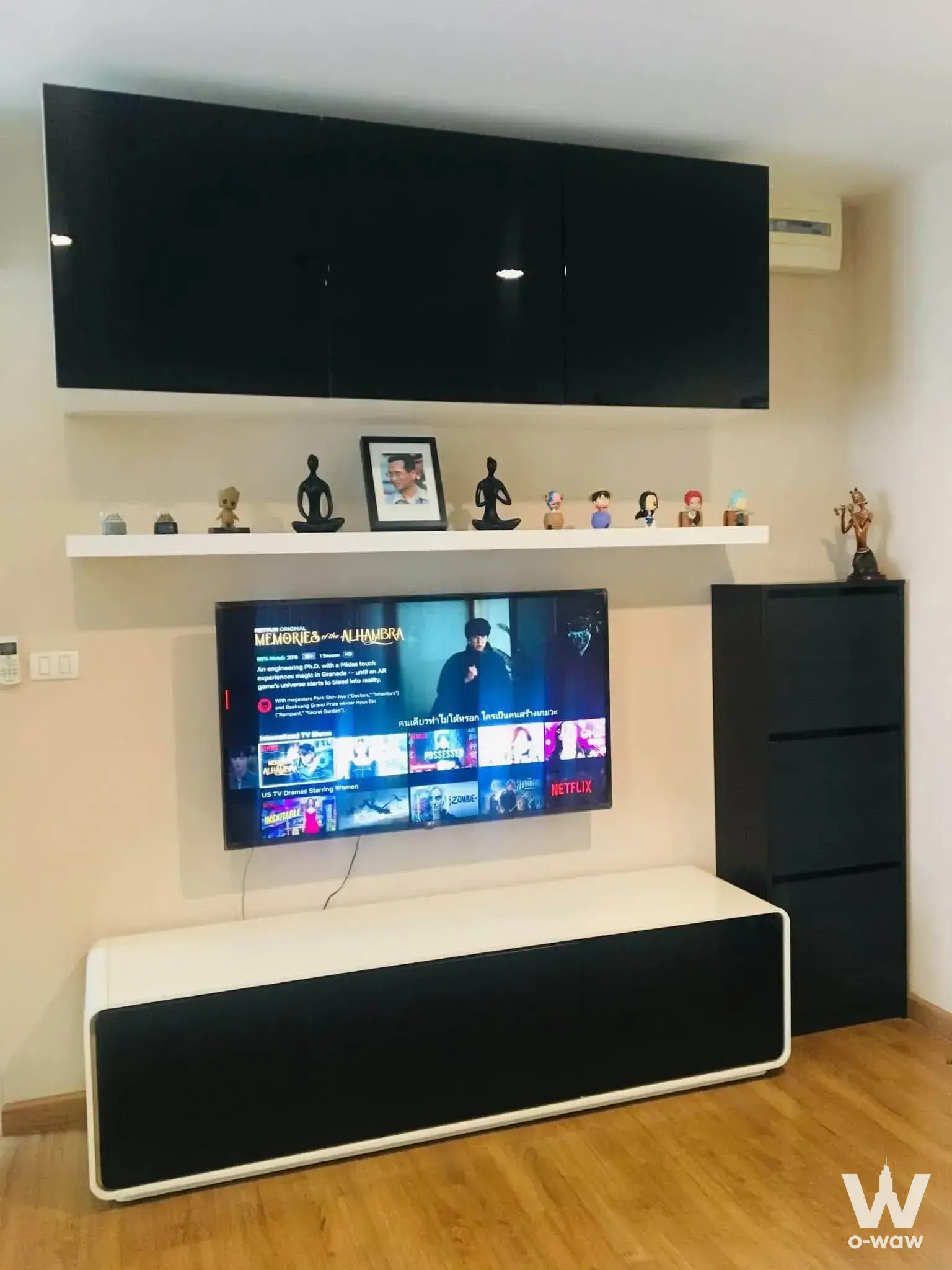 Living room in The Tree Interchange featuring a black media wall, floating shelf, and minimalist decor