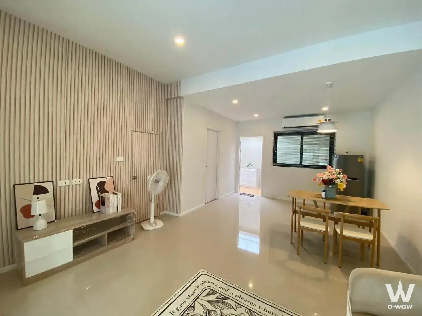 Open-plan living and dining area in a PLEX Onnut townhouse with wood slat wall, dining table, and glossy tiles