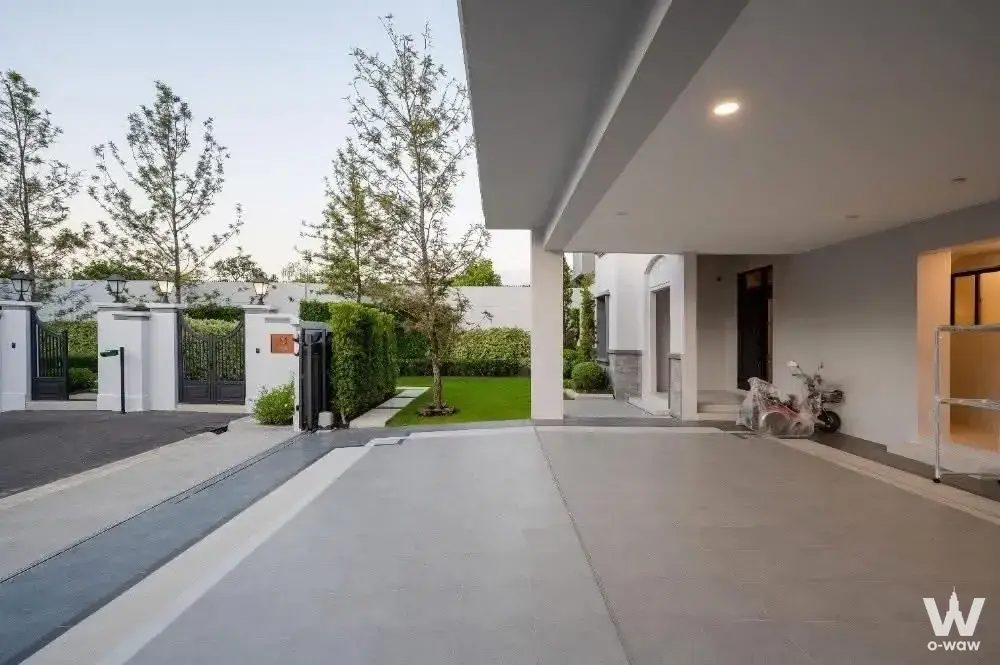Modern single-story house exterior with wide driveway and manicured lawn in Nantawan Rama 9