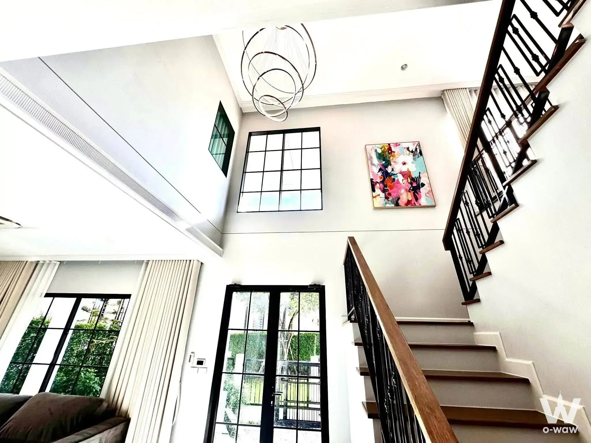 The double-height foyer in a 4-bed Setthasiri Bangna-Suvarnabhumi house has a staircase and black-framed windows