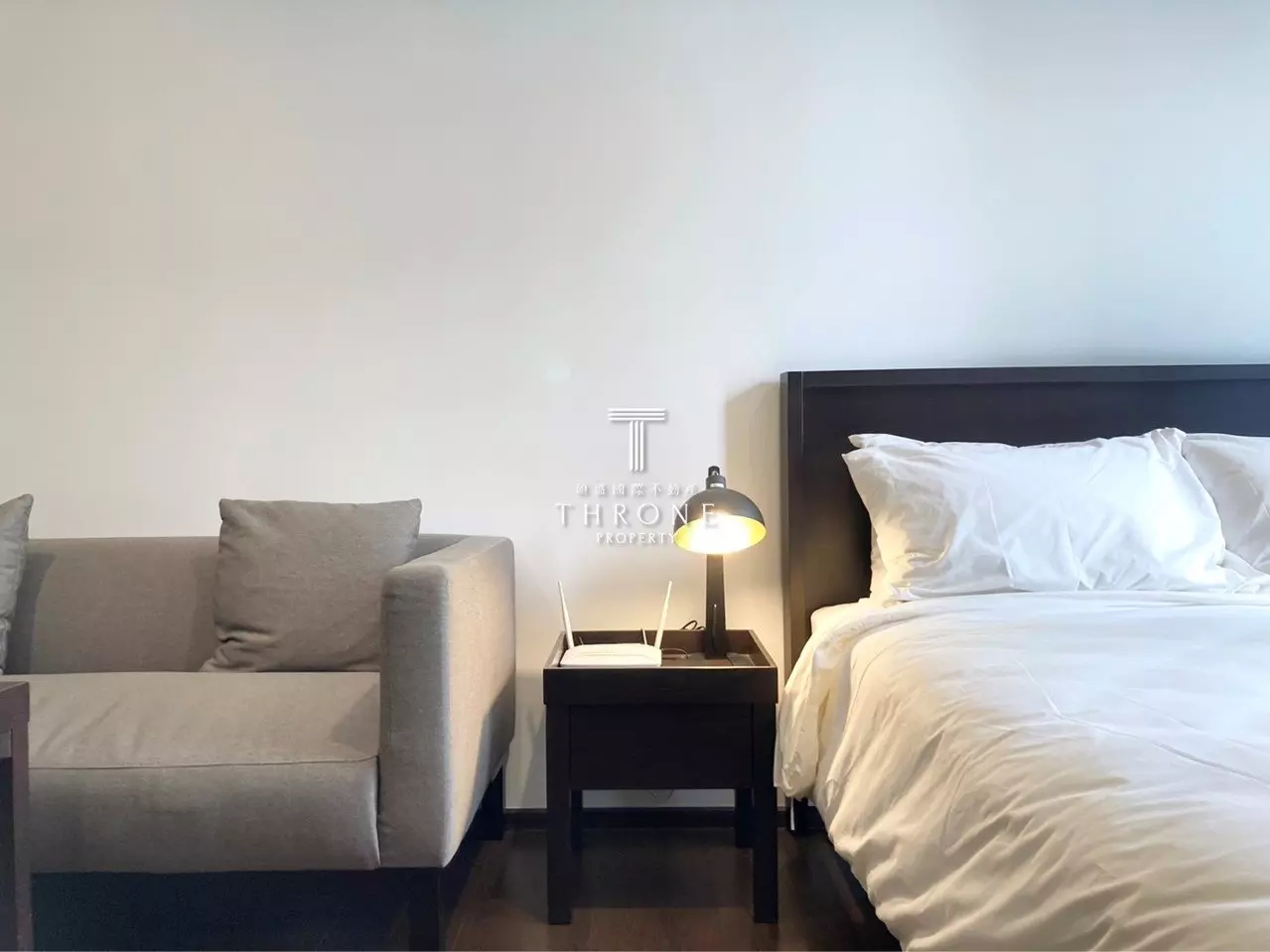 1-bed condo for rent in THE LINE Ratchathewi bedroom with dark wood headboard, white linens, and minimalist decor