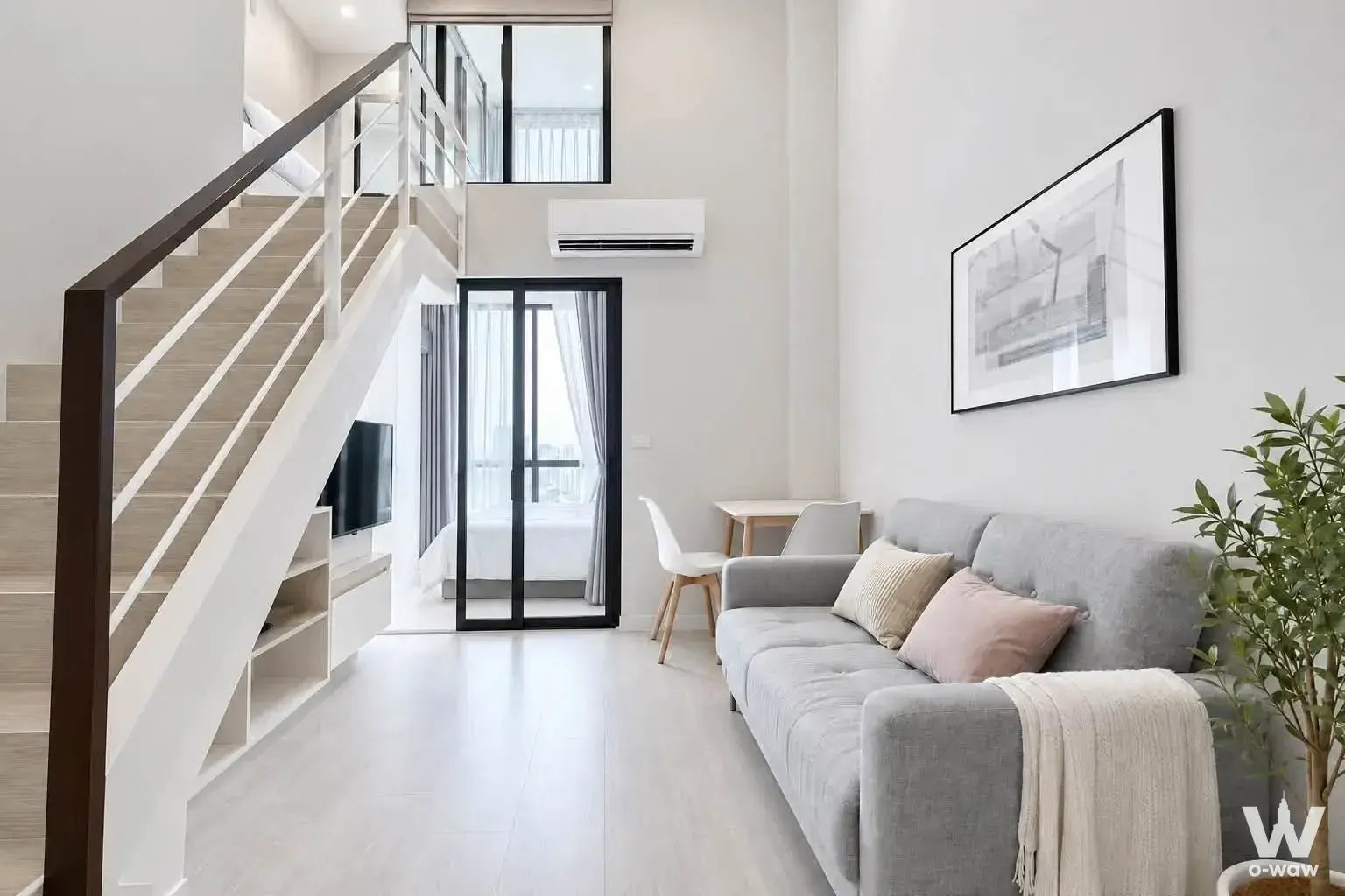 Double-height living room in a 2-bed Metro Sky Prachachuen condo for rent with open staircase and glass door
