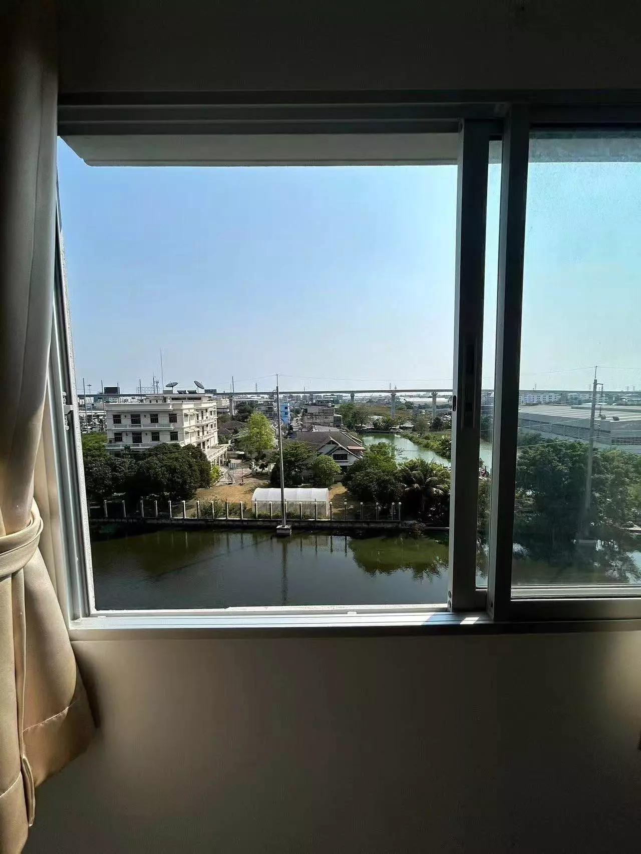 Beige curtain frames a canal view from this 2-bed condo for rent in Sena Kith Srinakarin-Sridan