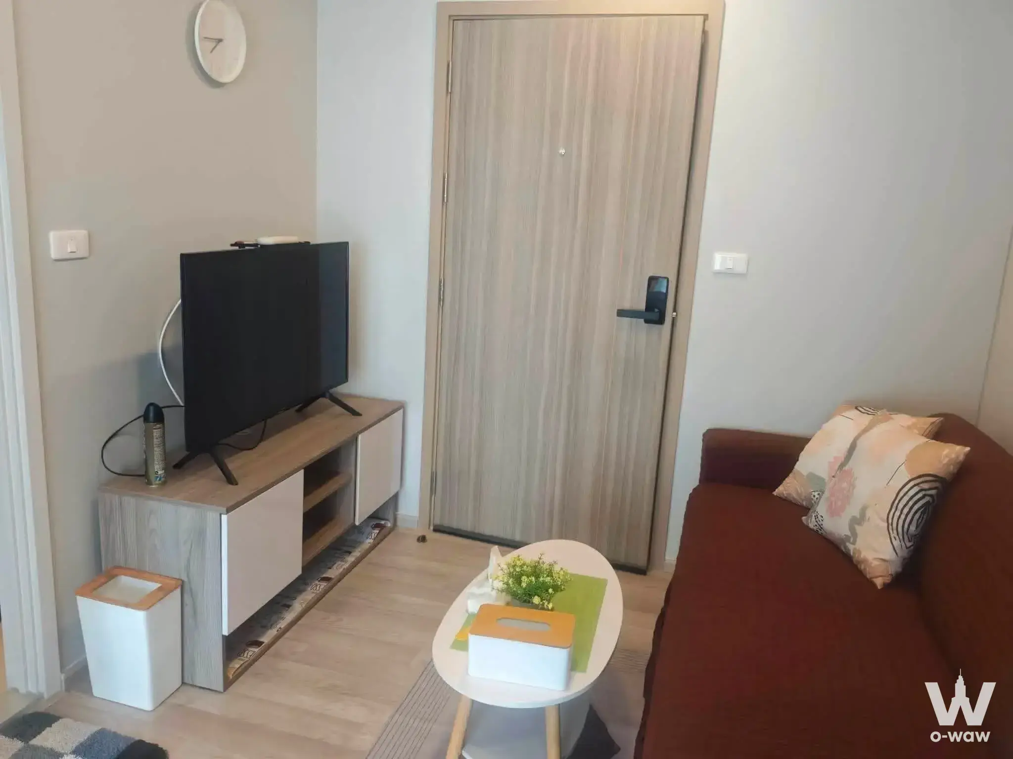 Tidy living area in Plum Condo Sukhumvit 62 with a dark brown sofa and white media console