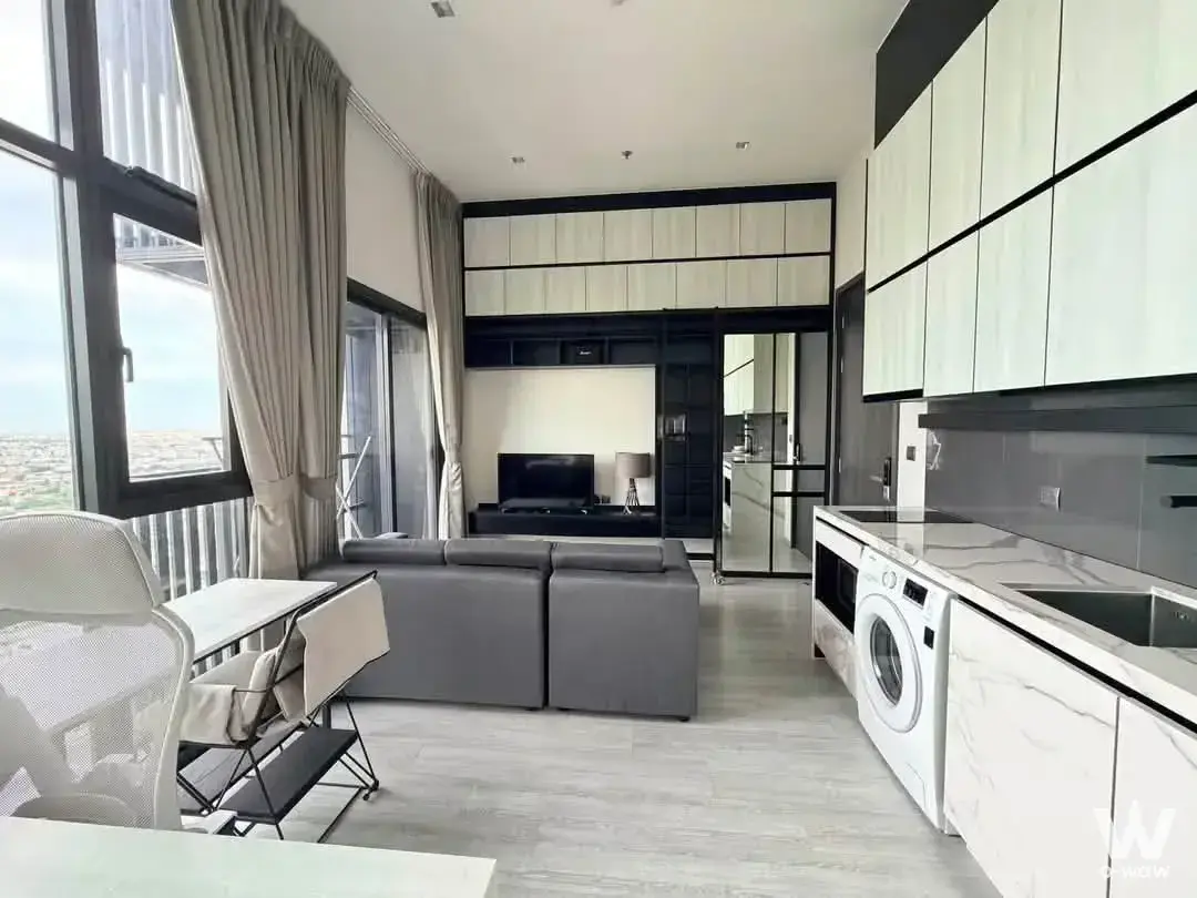 Open-plan living room in a 1-bed condo at THE LINE Sukhumvit 71 with grey sectional and marble kitchenette