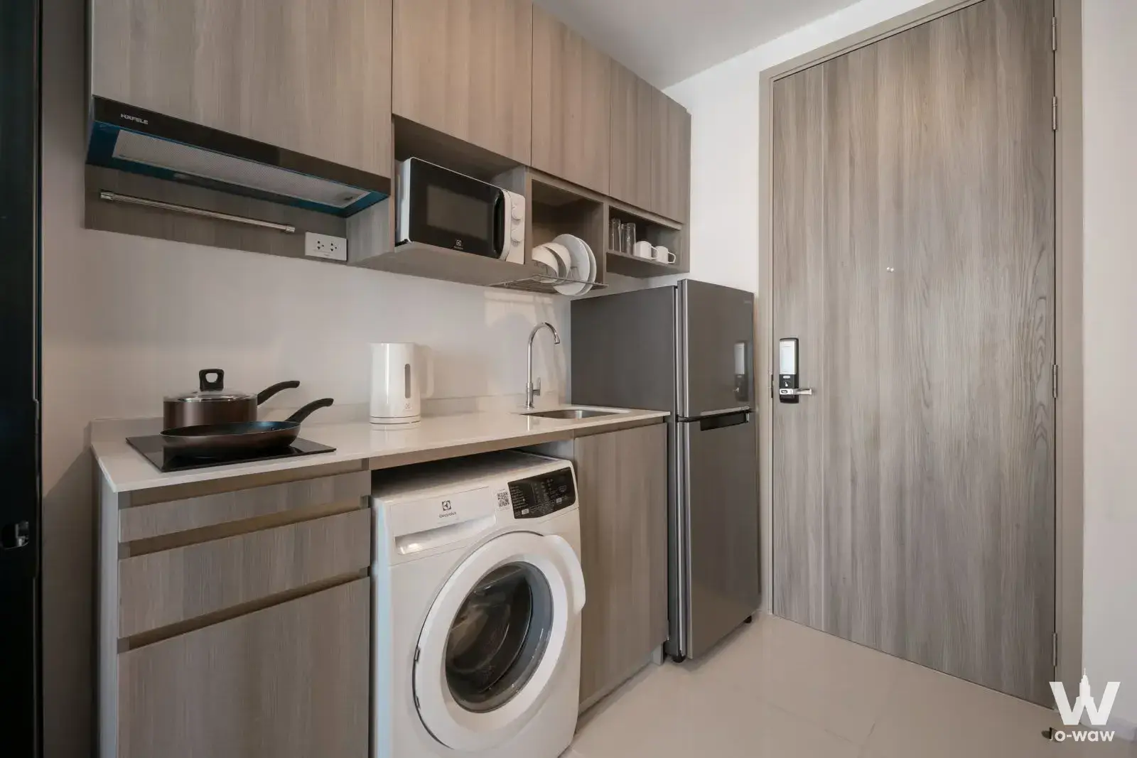 Compact kitchenette featuring light wood cabinets and an induction cooktop in Knightsbridge Sukhumvit-Thepharak