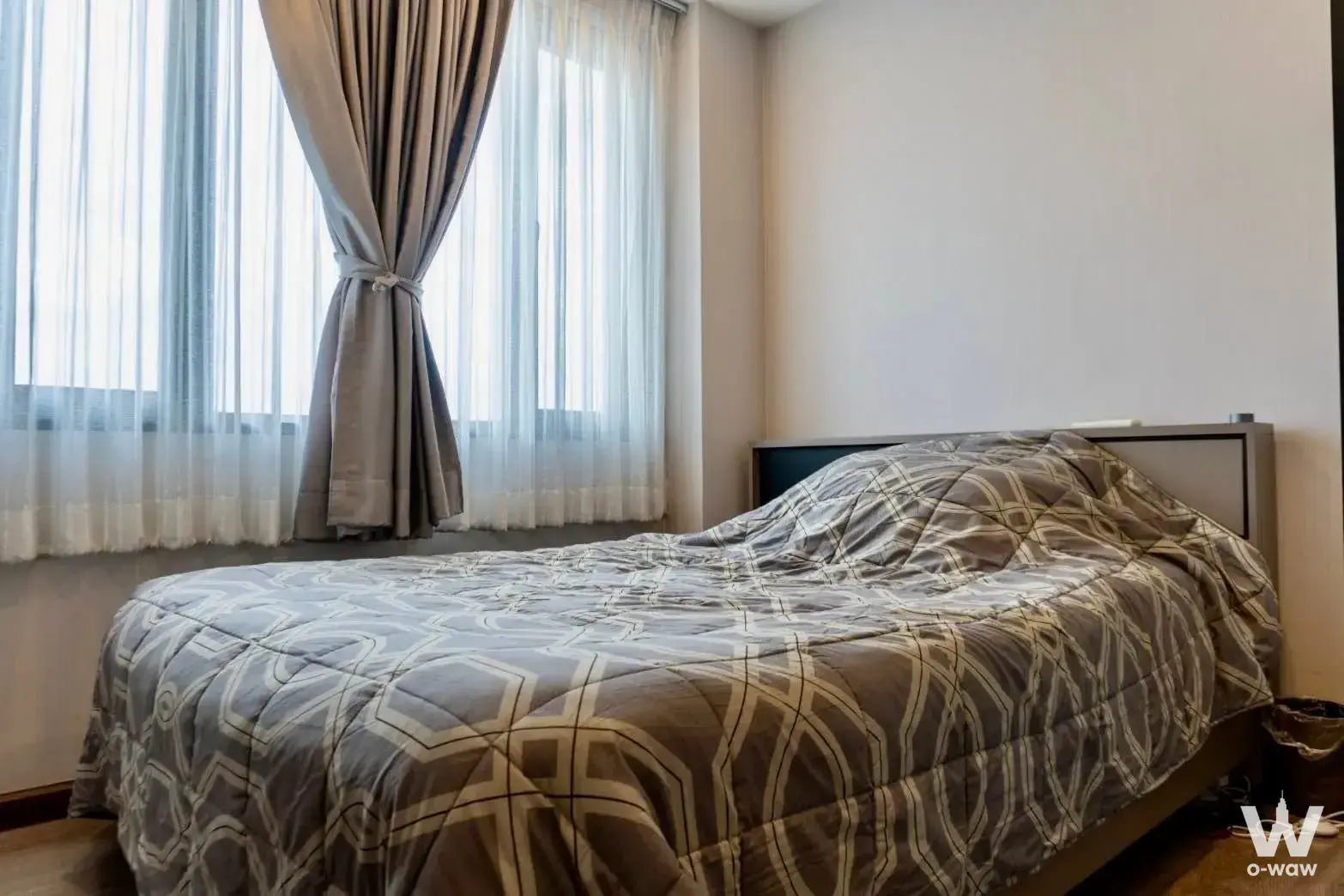 Queen bed with geometric bedding and floor-to-ceiling windows in Artisan Ratchada bedroom