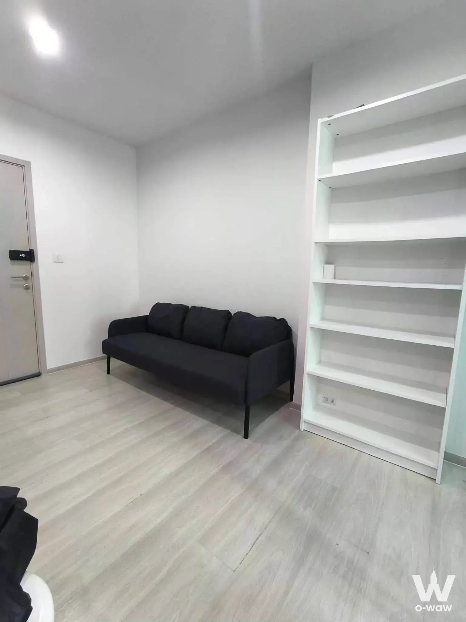 Minimalist living room in a Life Pinklao 1-bed rental with grey sofa and smart lock entry door