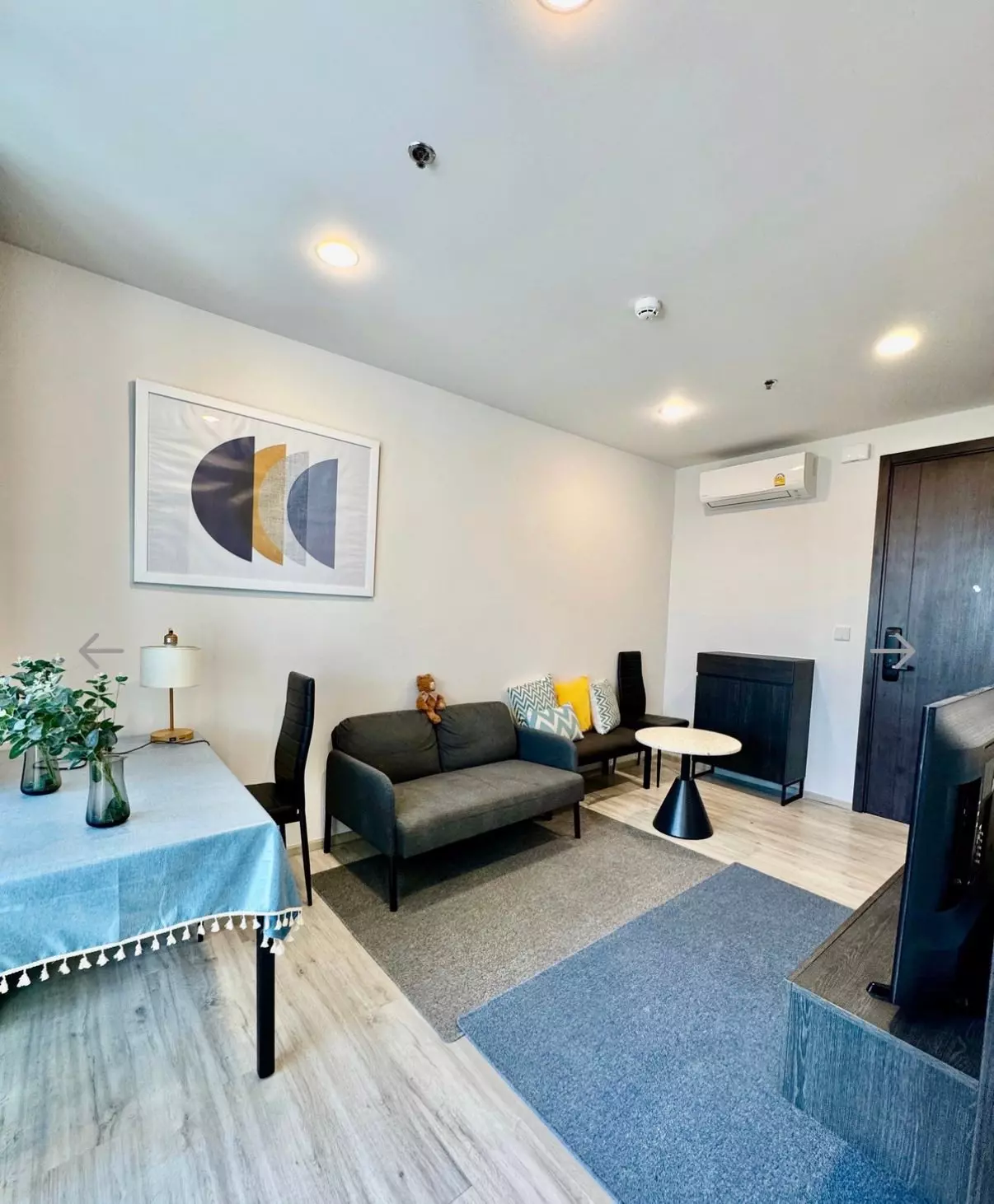 Modern living room with grey sofa and wood floors in an XT Huai Khwang condo for rent