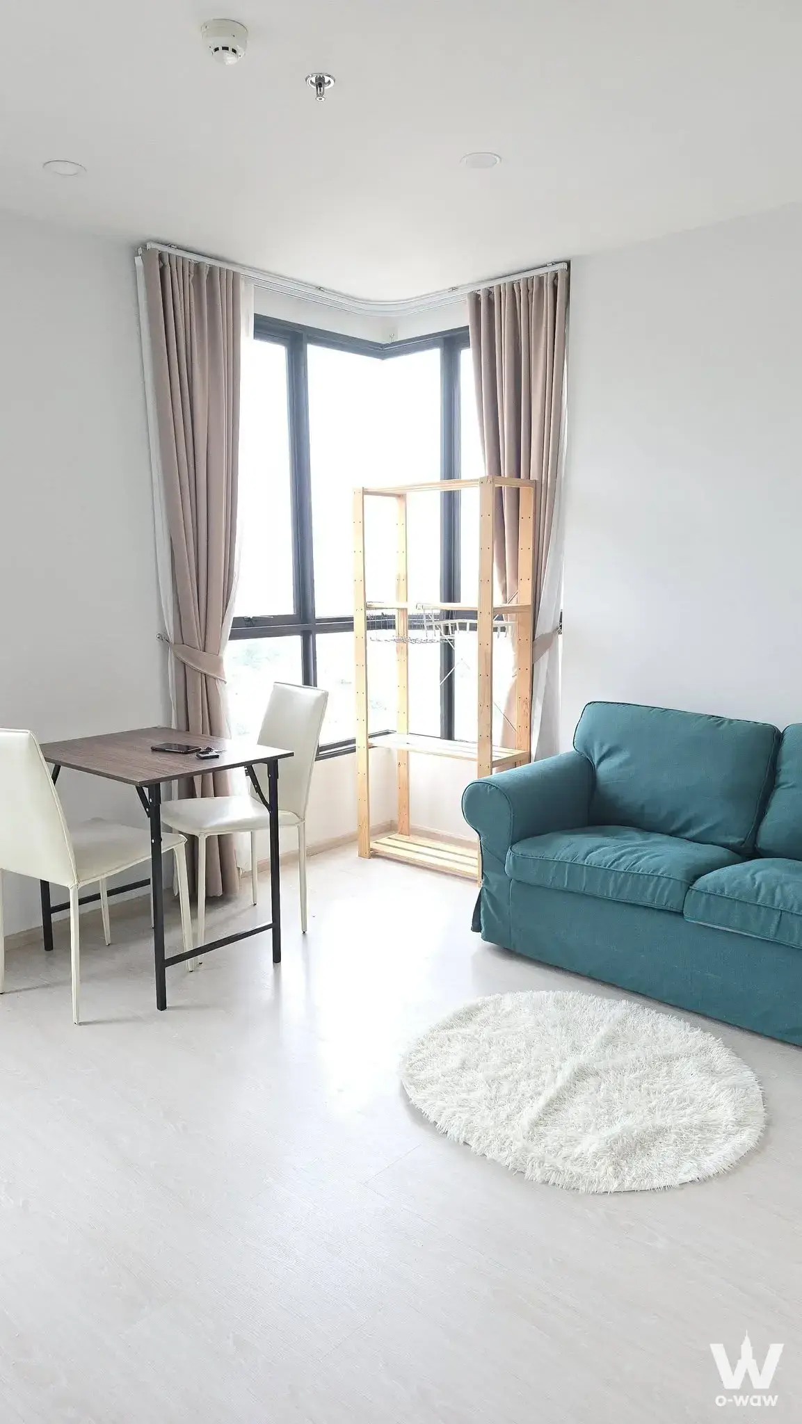 Bright 1-bed condo living room in ELIO DEL NEST with teal sofa and bay window