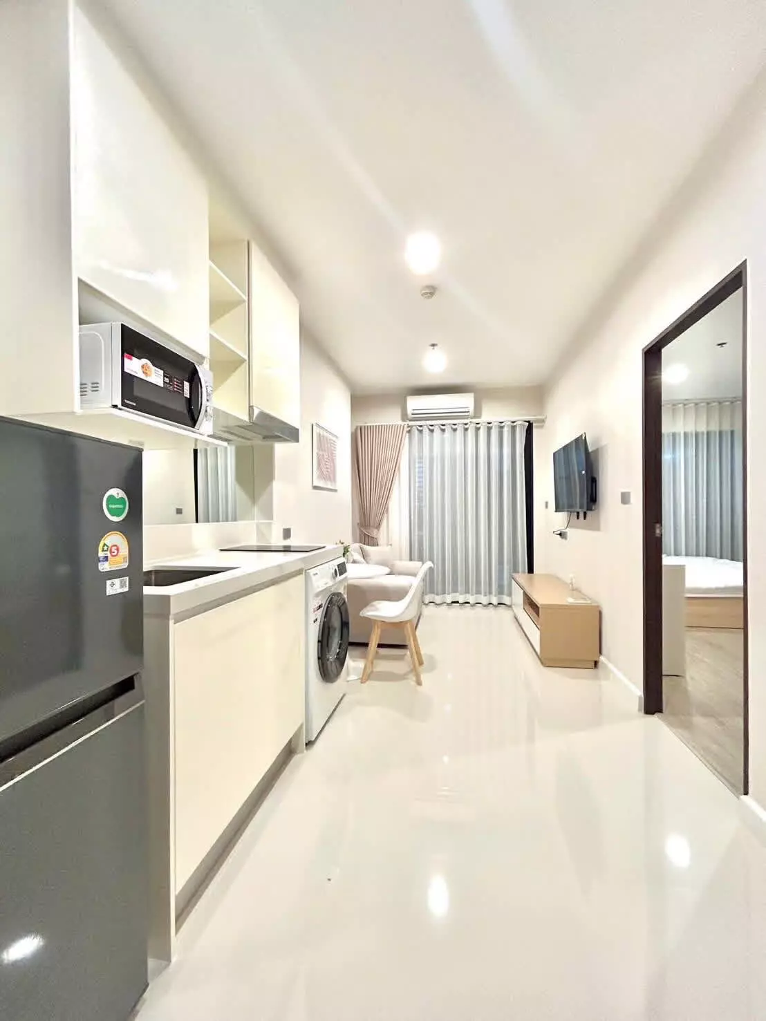 The Sky Sukhumvit 1-bed condo kitchenette with cream cabinets and stainless steel fridge