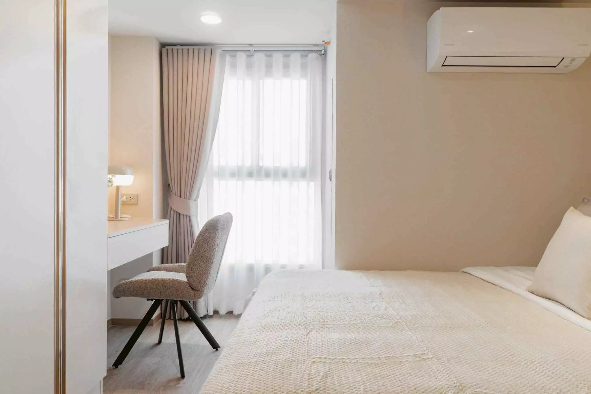 Cozy bedroom in a Culture Chula 1-bed condo featuring floor-to-ceiling windows and a built-in white desk with lamp