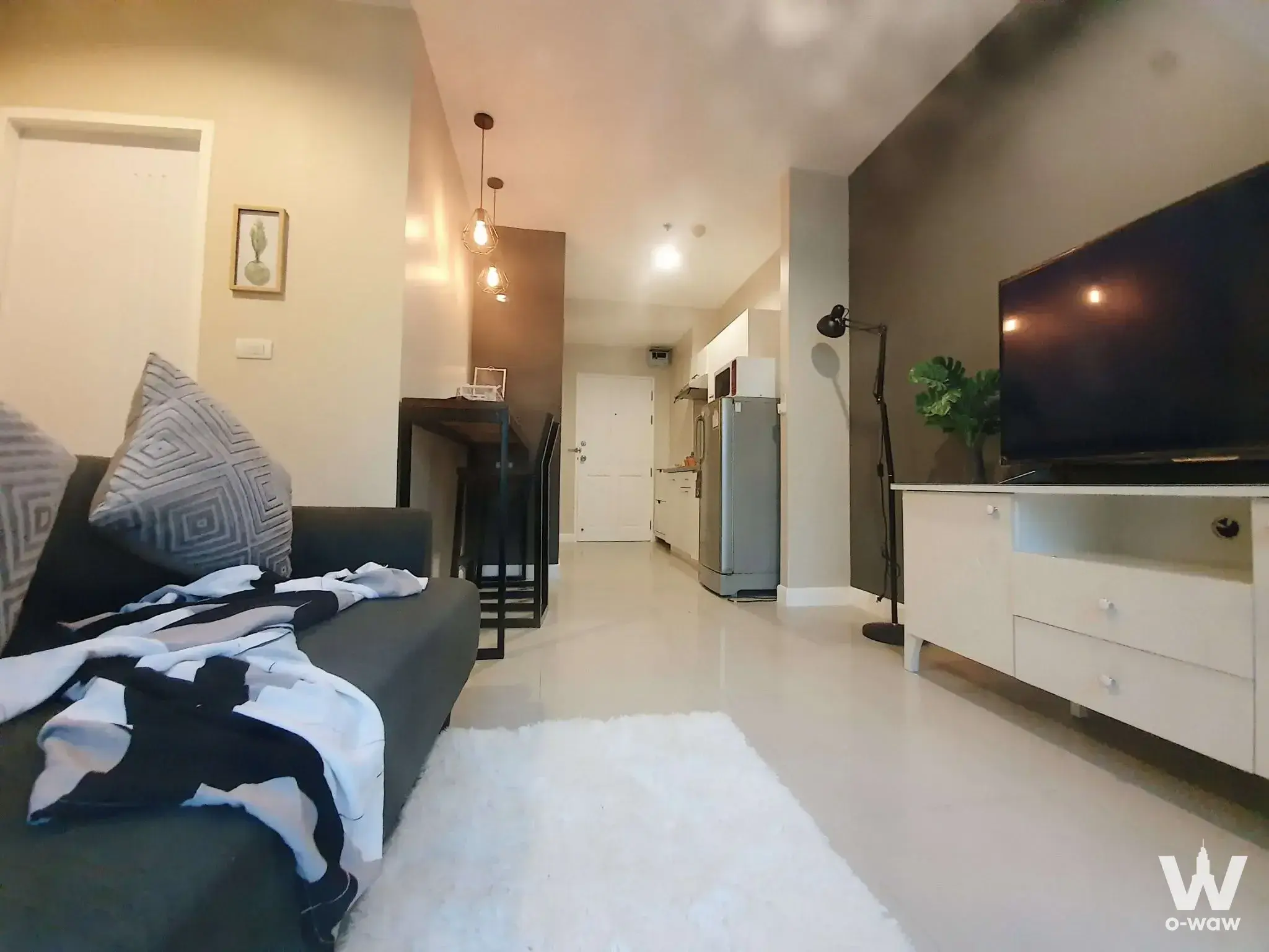 Open-plan living room in a 1-bed City Home Sukhumvit rental with grey sofa and white tile floor