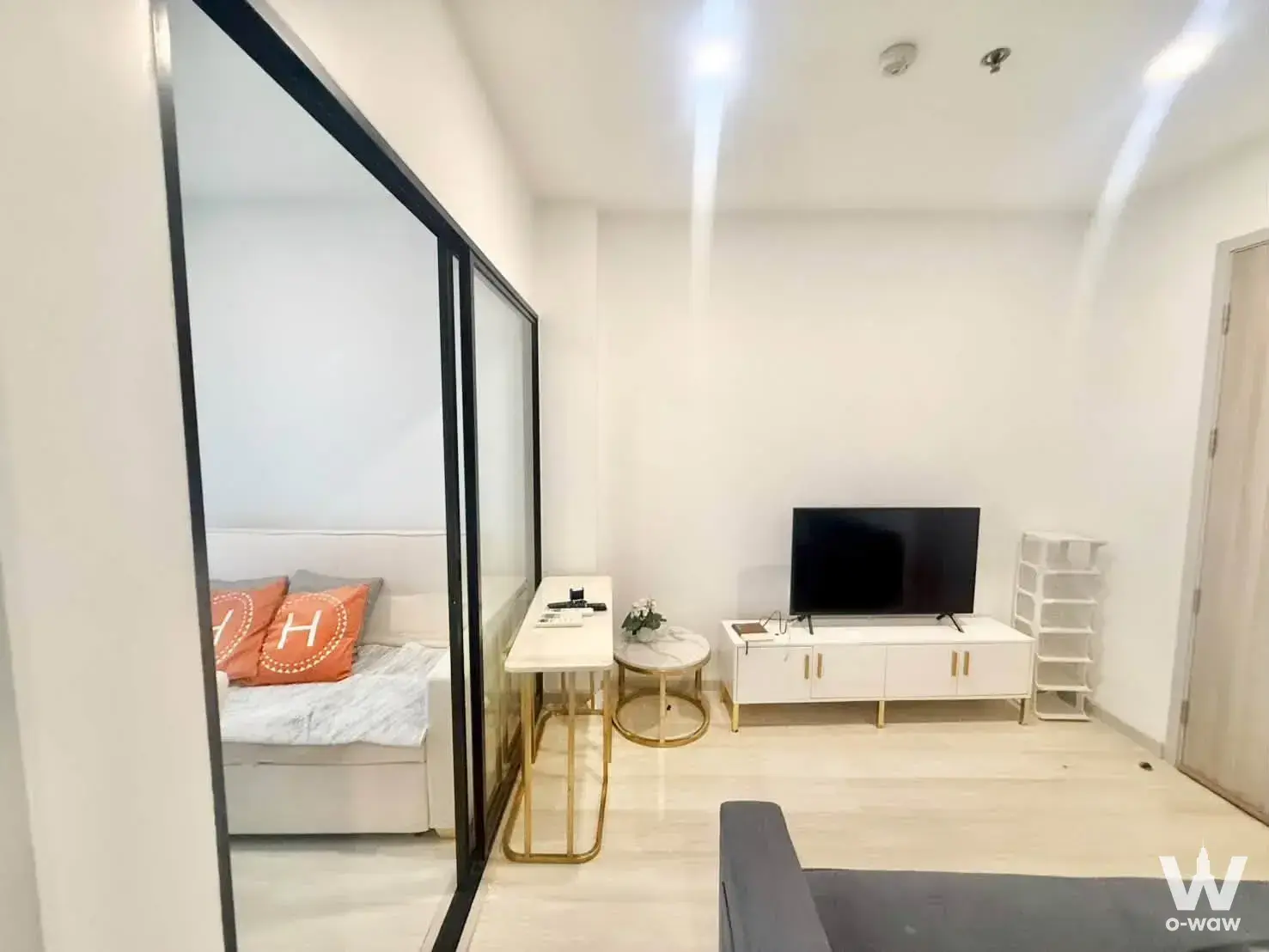 Modern living area with orange accent pillows and glass partition in KnightsBridge Prime Sathon