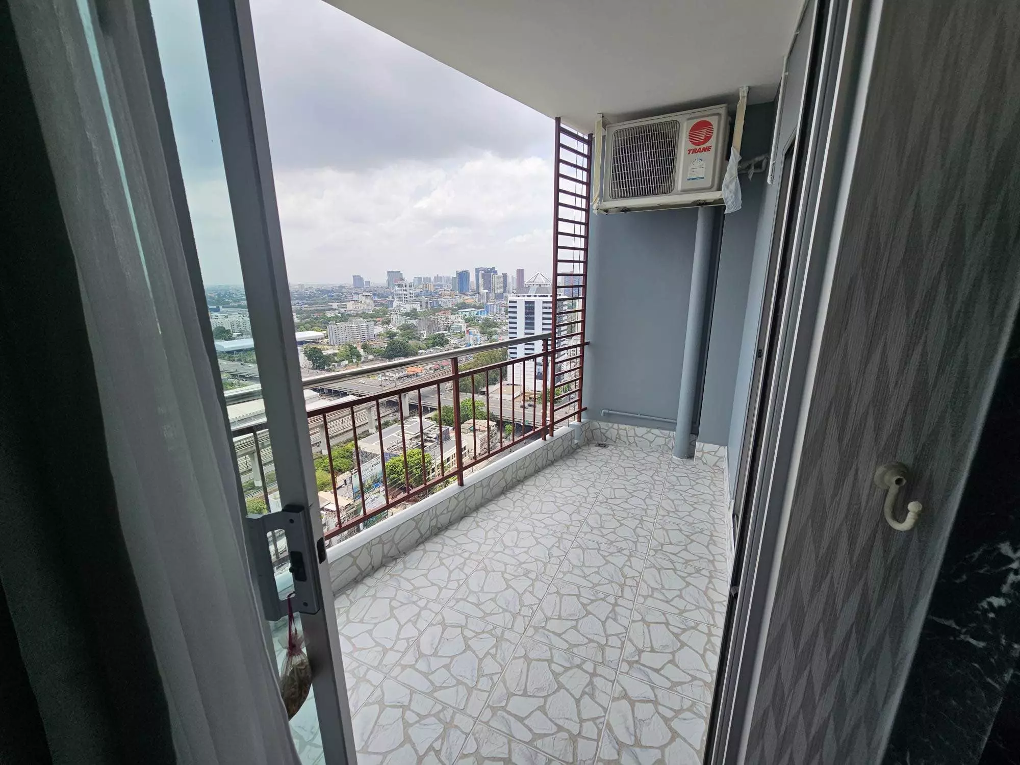 Narrow balcony at Supalai Park Ekkamai featuring stone tiles and a wide city skyline view