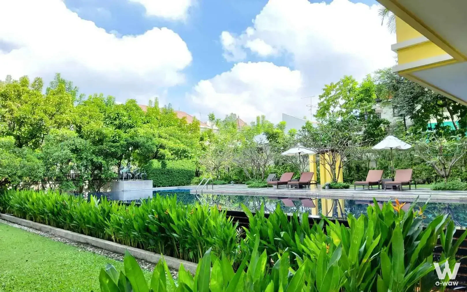 The Lofts Yennakart outdoor pool area with lounge chairs, umbrellas, and tropical landscaping