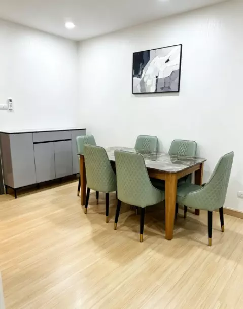 Dining room in a Ramkhamhaeng condo featuring sage green chairs and marble table