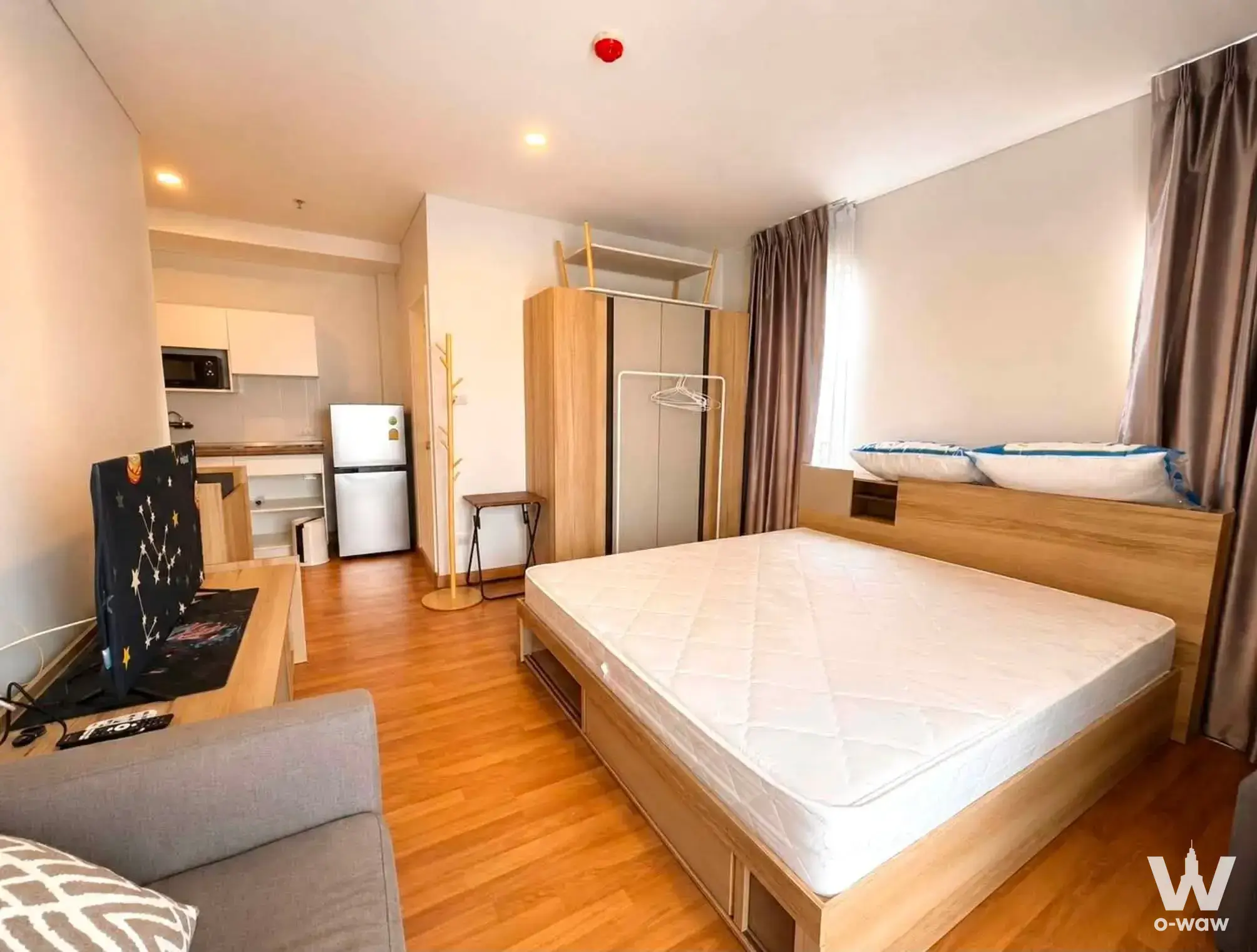 Furnished studio apartment with light wood flooring and kitchenette for rent at Lumpini Place Rama 3