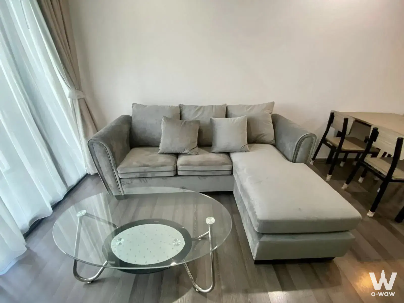 Living room with grey sectional sofa and glass coffee table in THE BASE Park West