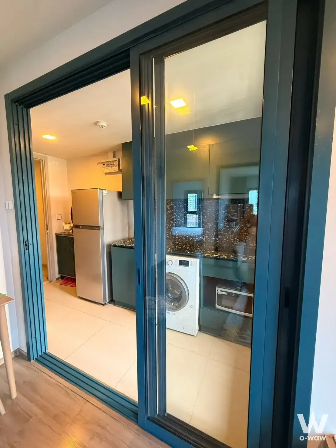 Kitchen area in THE BASE Sukhumvit 50 1-bed rental with dark green cabinets and granite countertops