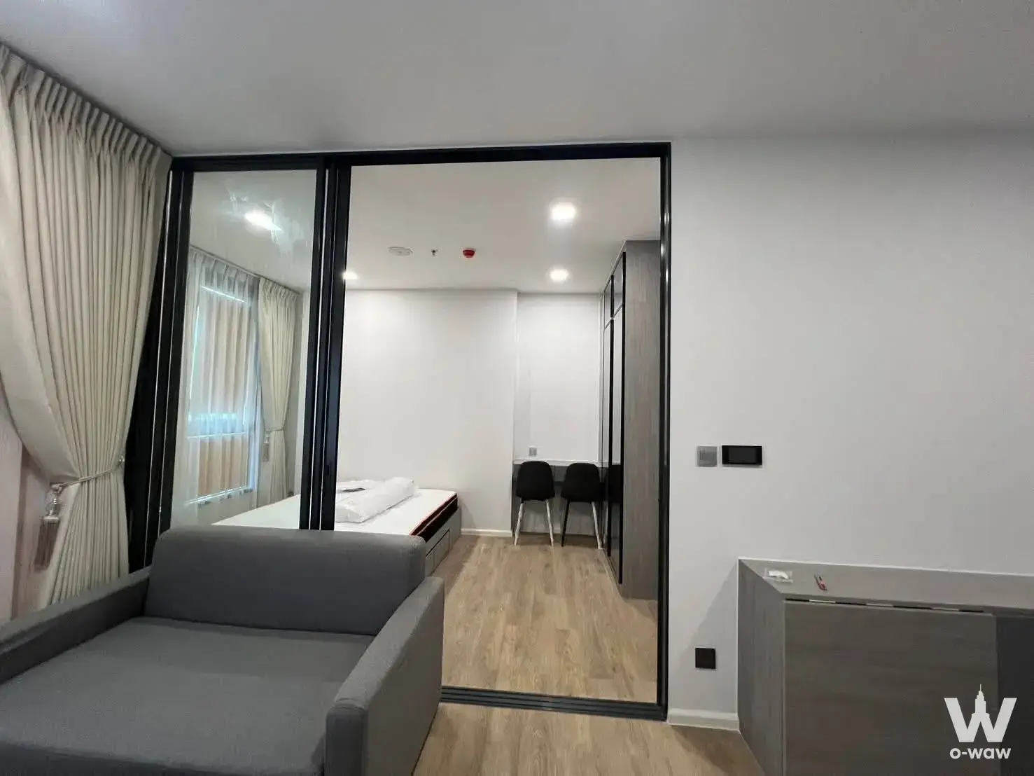 Open-plan 1-bed condo in Modiz Rihm Ramkhamhaeng featuring a glass partition and light wood flooring