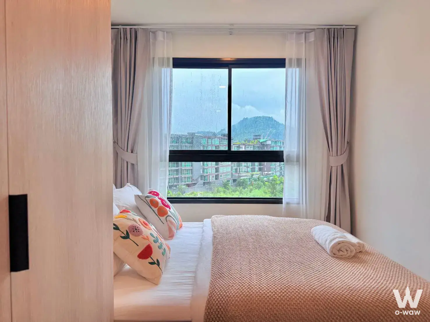Bedroom in a 1-bed condo for rent at The Base Bukit Phuket with white linens and a large window overlooking the city