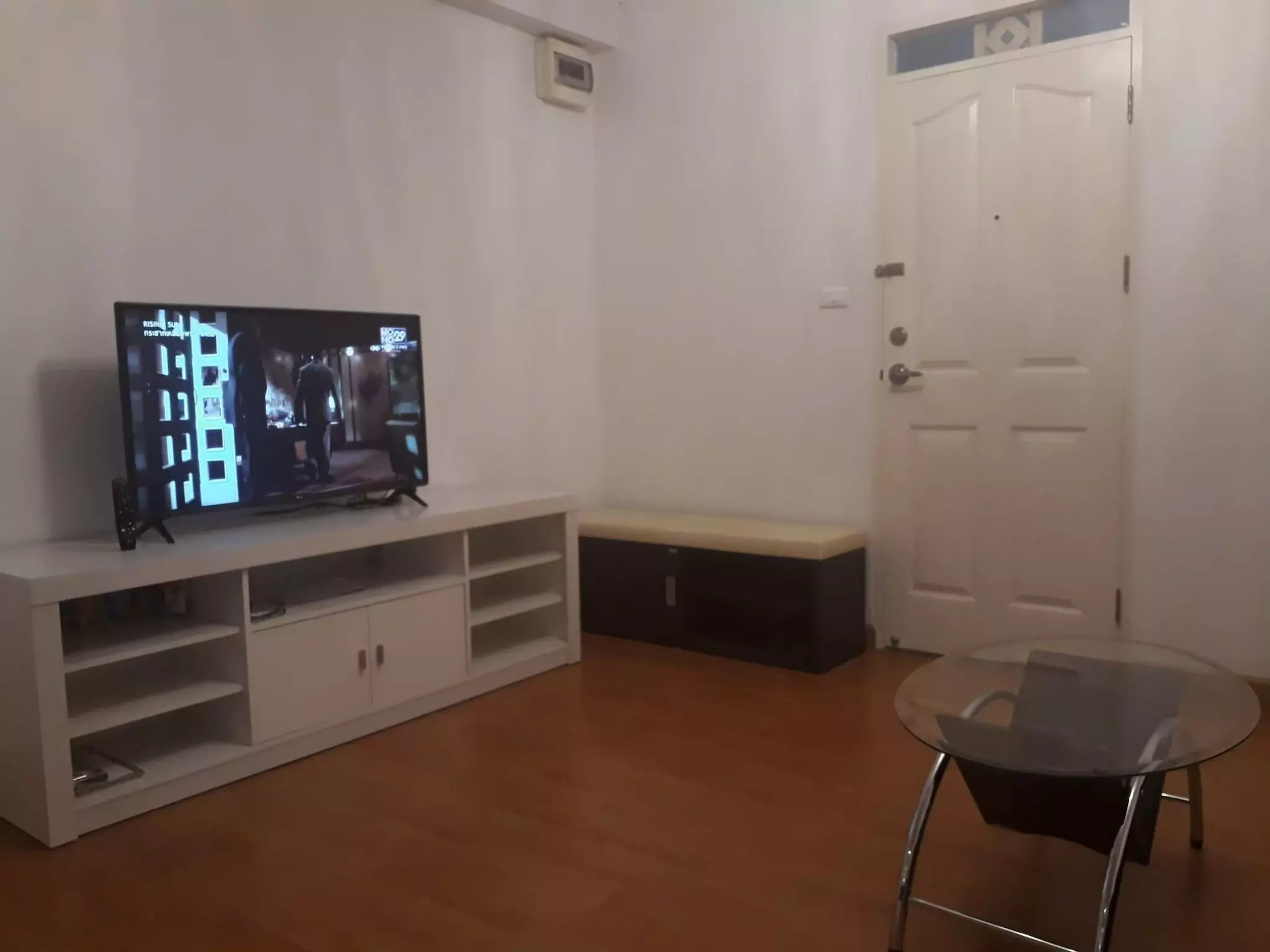 Modest living room for rent in City Home Sukhumvit with white walls, laminate flooring, and TV console