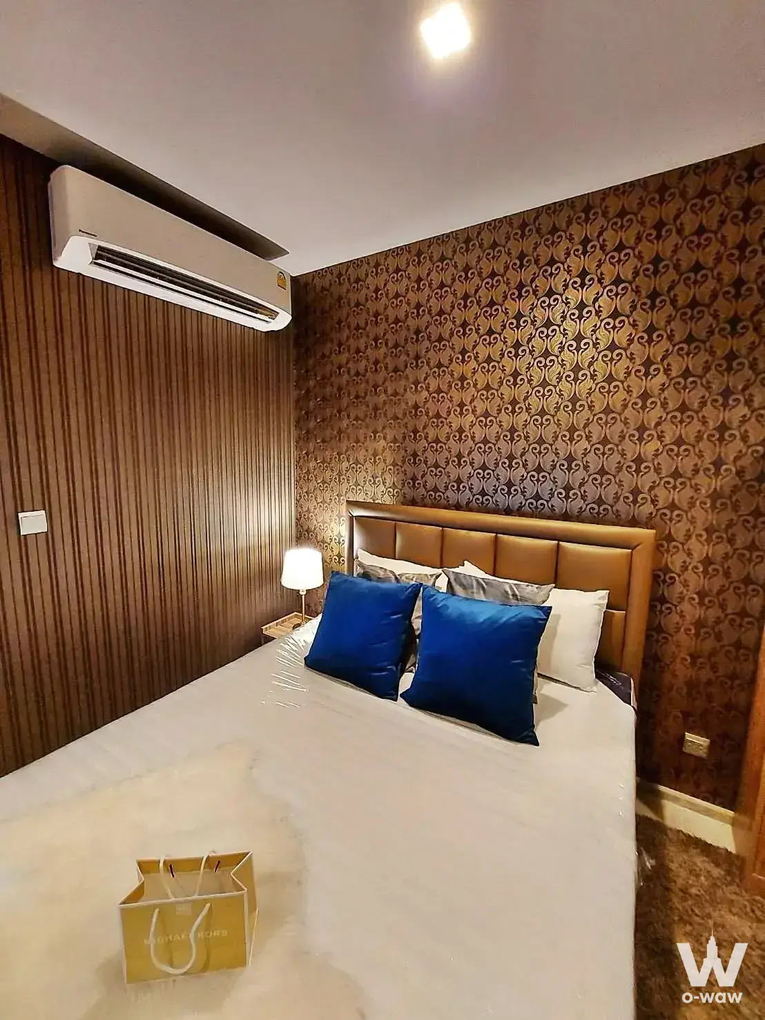 Modern bedroom in Life Asoke Rama 9 with tan leather headboard and brown swirl patterned wallpaper