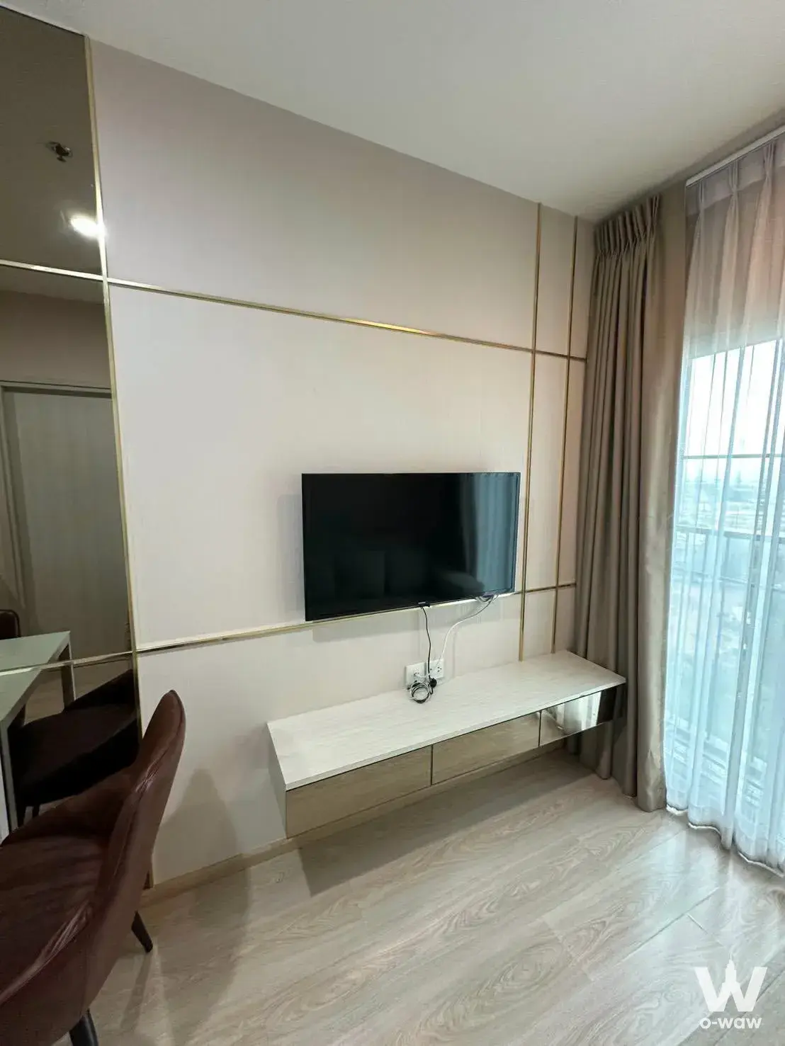 Living room in Noble Revolve Ratchada 2 condo for sale with cream gold feature wall and city view