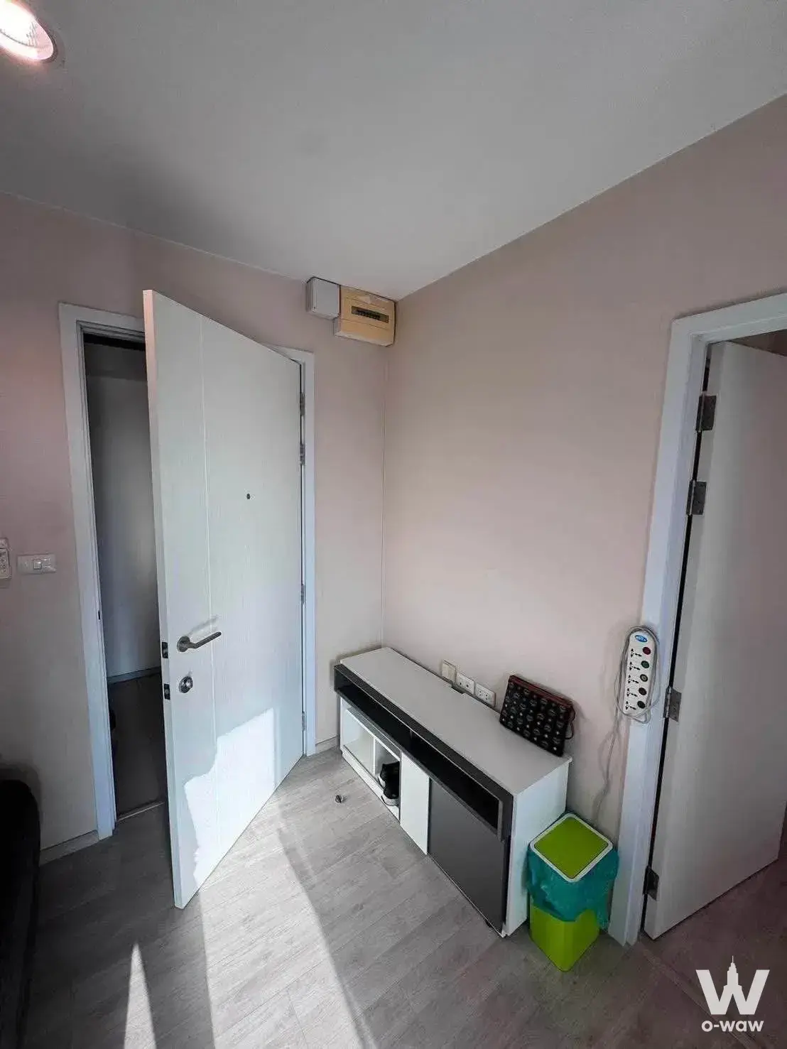 Tidy entryway in a Plum Condo Central Station unit with pale pink walls, white entrance door, and low media console