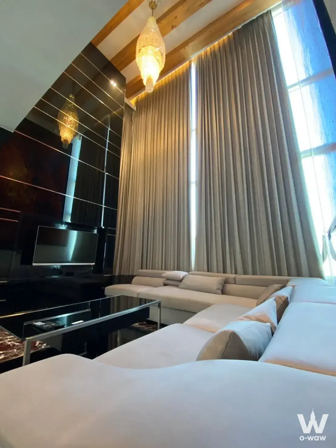 3-bed condo for sale in Wind Sukhumvit 23 showcasing luxury high-ceiling space with crystal chandelier and black glossy