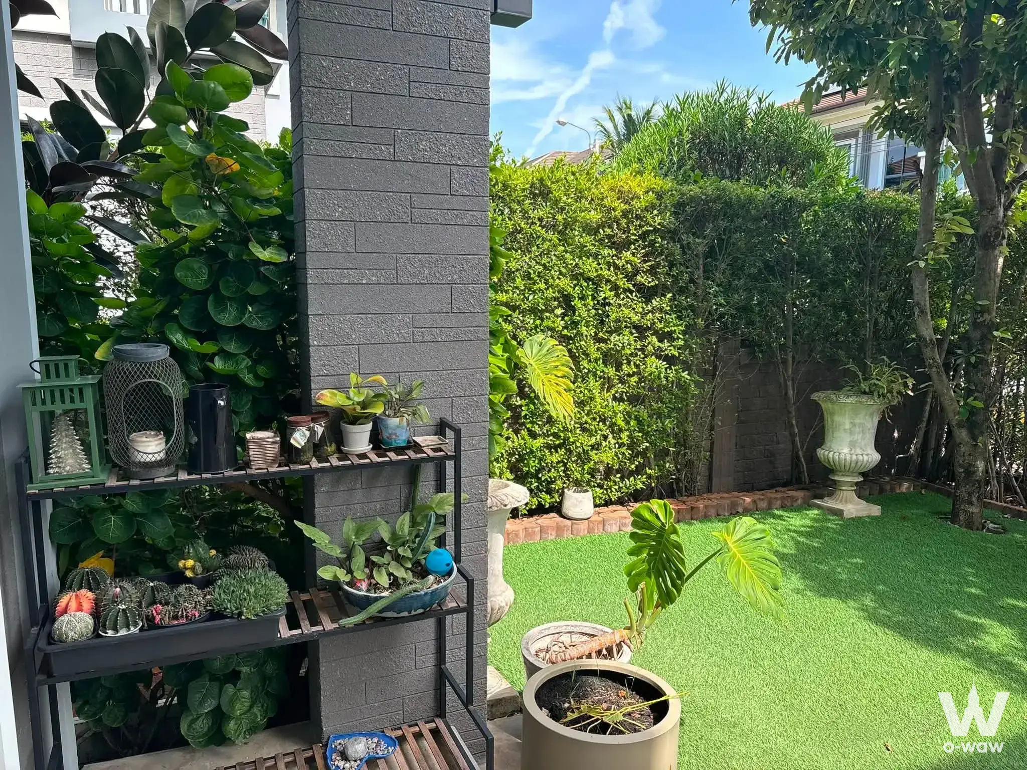 Private garden patio at Patio Phatthanakan 38 townhouse with lush greenery, brick pillars, and stone urns