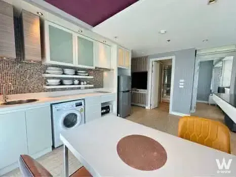 Open-plan kitchen with white cabinets and purple ceiling accent in a 1-bed condo at La Santir