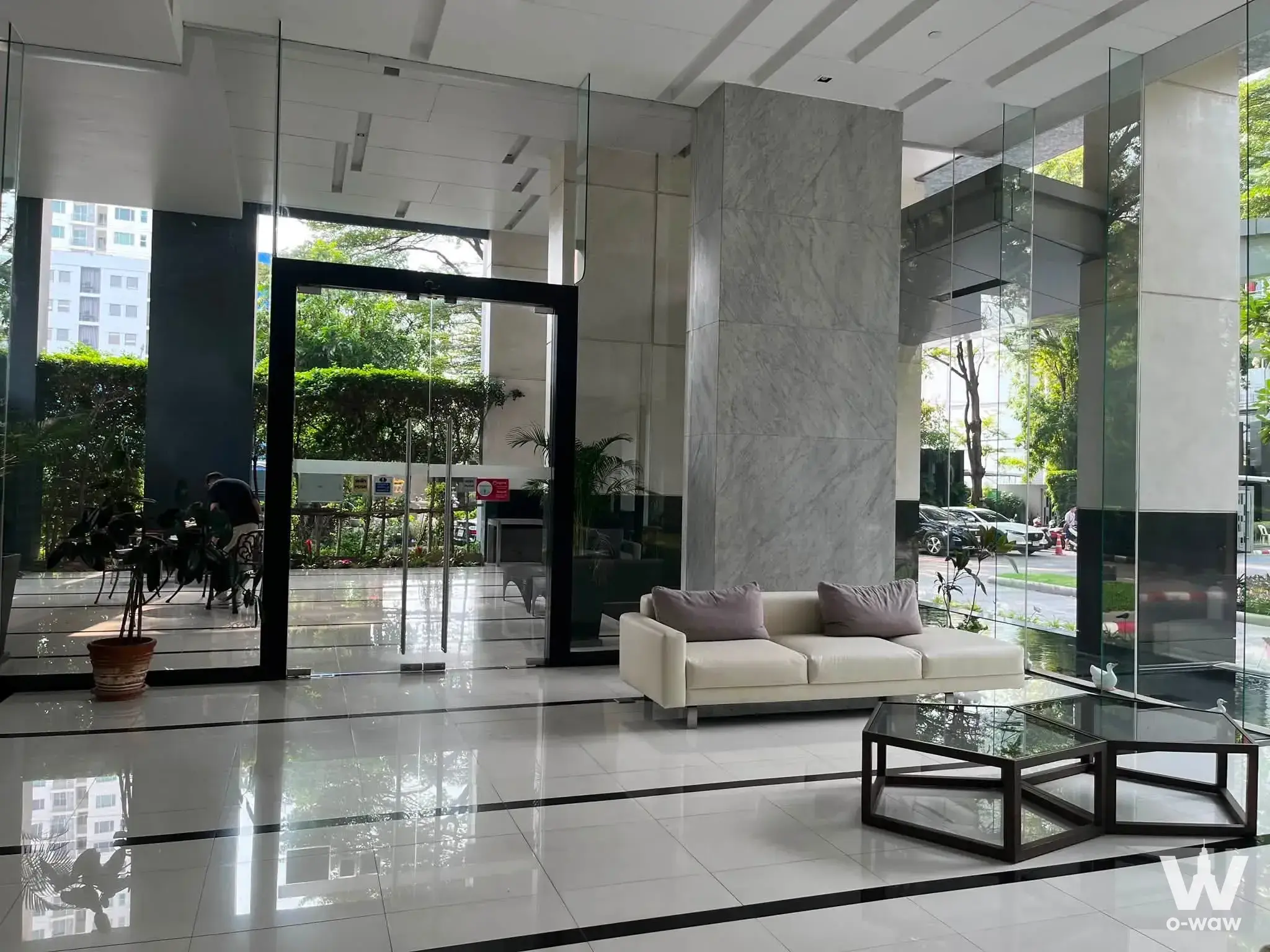 Luxury lobby featuring polished white marble floors, glass walls, and cream leather seating in Hive Sathorn Condo