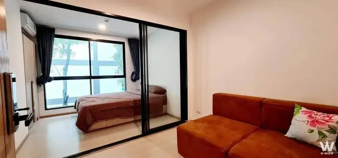 1-bed condo for sale in The Excel Groove studio apartment with burnt-orange sofa and glass partition bedroom