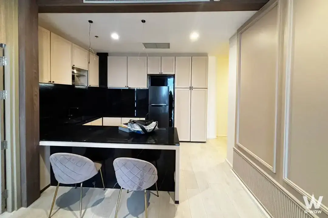 Modern kitchen in Noble Ploenchit featuring black granite island and cream cabinets